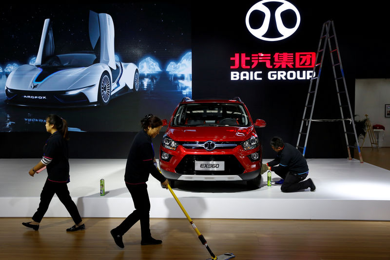 © Reuters. FILE PHOTO: People clean the floor at the stall of the BAIC Group automobile maker at the IEEV New Energy Vehicles Exhibition in Beijing