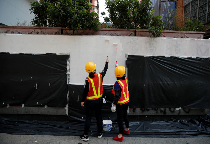 © Reuters. Trabajadores pintan para cubrir palabras que fueron escritas durante la protesta antigubernamental del domingo en las paredes de una sucursal bancaria en Hong Kong, China, el 23 de octubre de 2019