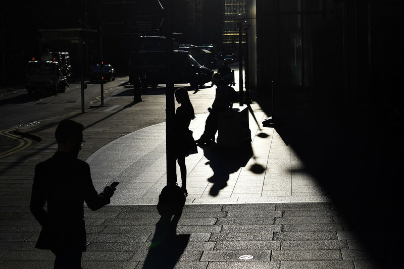 © Reuters. The early morning sun silhouettes commuters as they make their way through Canary Wharf in London