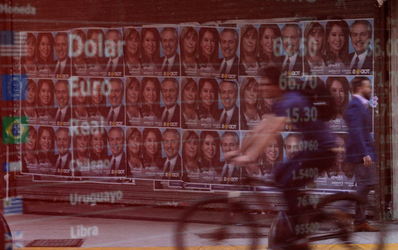 © Reuters. FILE PHOTO:  Campaign poster for opposition presidential candidate Alberto Fernandez and his running mate Cristina Fernandez are reflected in an electronic board that shows currency exchange in Buenos Aires' financial district