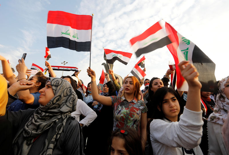 © Reuters. Women demonstrators hold Iraqi flags as they take part in a protest over corruption, lack of jobs, and poor services, in Baghdad