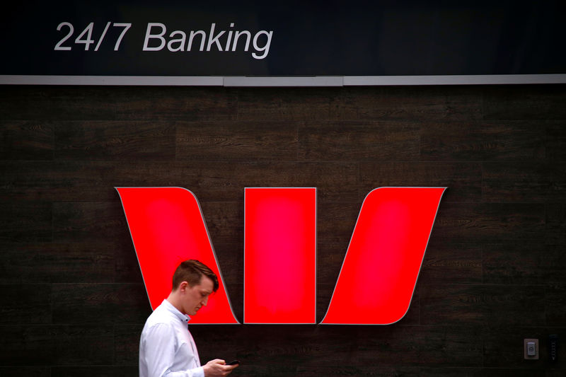 © Reuters. A pedestrian looks at his phone as he walks past a logo for Australia's Westpac Banking Corp located outside a branch in central Sydney