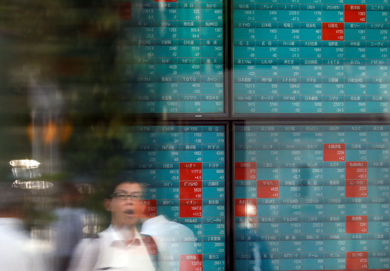 © Reuters. A man is reflected on a stock quotation board outside a brokerage in Tokyo