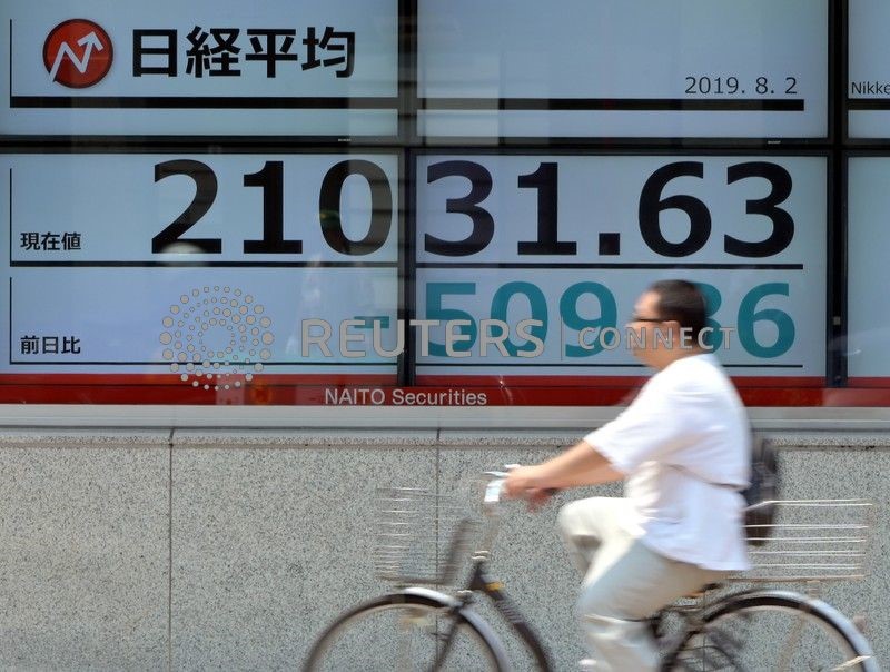 © Reuters. Ciclista se locomove em frente a painel de ações em Tóquio