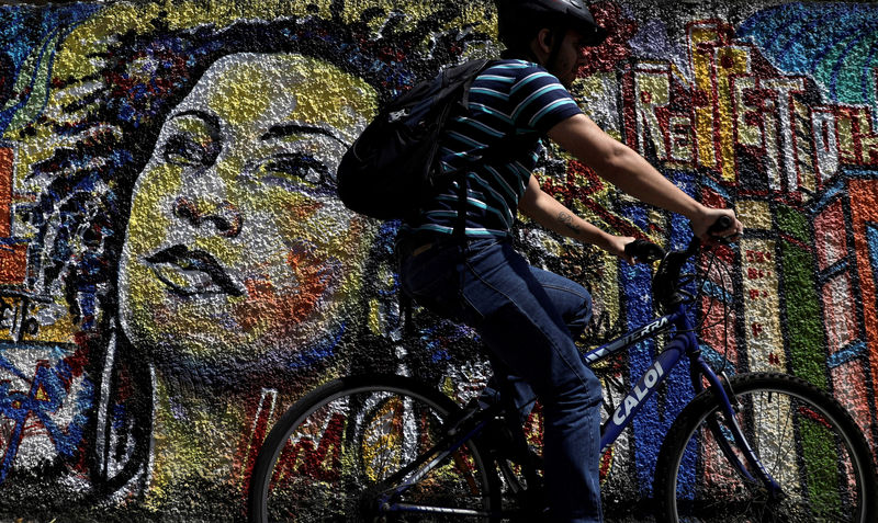 © Reuters. FILE PHOTO: A man rides past a graffiti in tribute of late councilwoman Marielle Franco, murdered last year in Rio de Janeiro