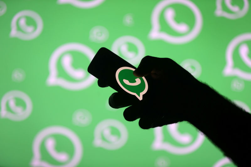 © Reuters. FILE PHOTO: A man poses with a smartphone in front of displayed Whatsapp logo in this illustration