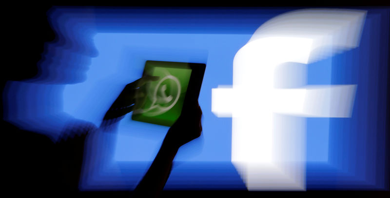 © Reuters. FILE PHOTO: Woman holds a tablet displaying WhatsApp's logo in front of the screen with the Facebook logo in this photo illustration taken in Prague
