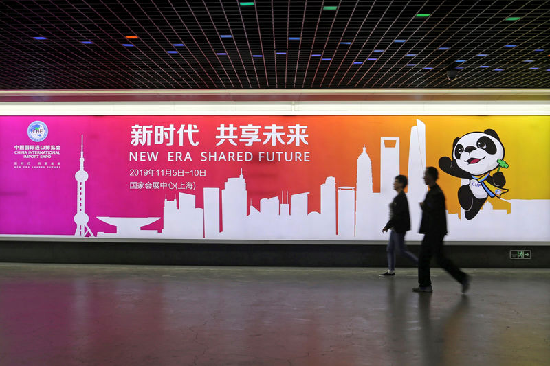 © Reuters. La gente pasa junto a un anuncio de la próxima Exposición Internacional de Importación de China en una estación de tren en Shanghai