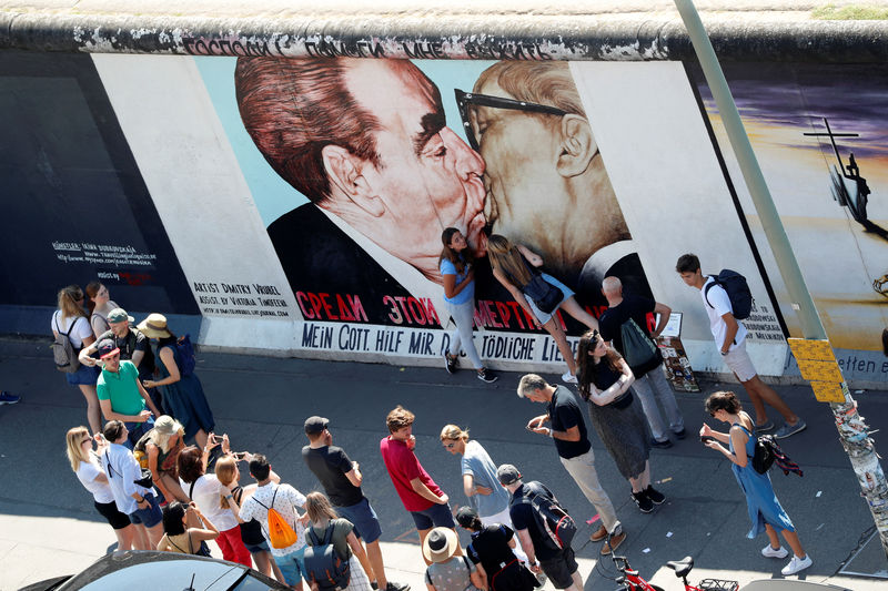 © Reuters. Turistas em frente a grafitti em mural em Berlim