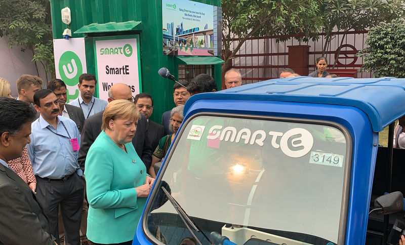 © Reuters. FILE PHOTO: German Chancellor Angela Merkel stands next to an electric vehicle during her visit to a solar powered metro station at Dwarka in New Delhi