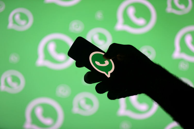© Reuters. FILE PHOTO: A man poses with a smartphone in front of displayed Whatsapp logo in this illustration picture