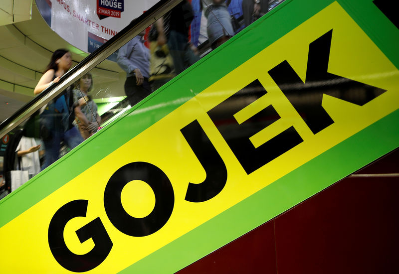 © Reuters. FILE PHOTO: Commuters pass by a Gojek advertisement in Singapore