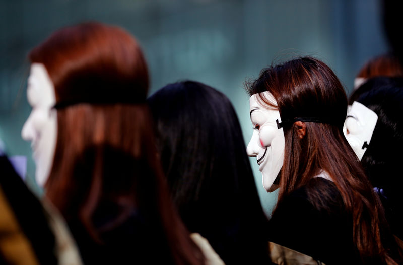 © Reuters. University students wearing Guy Fawkes masks pose for a photoshot to support anti-government protests before their graduation ceremony at the Hong Kong Polytechnic University in Hong Kong