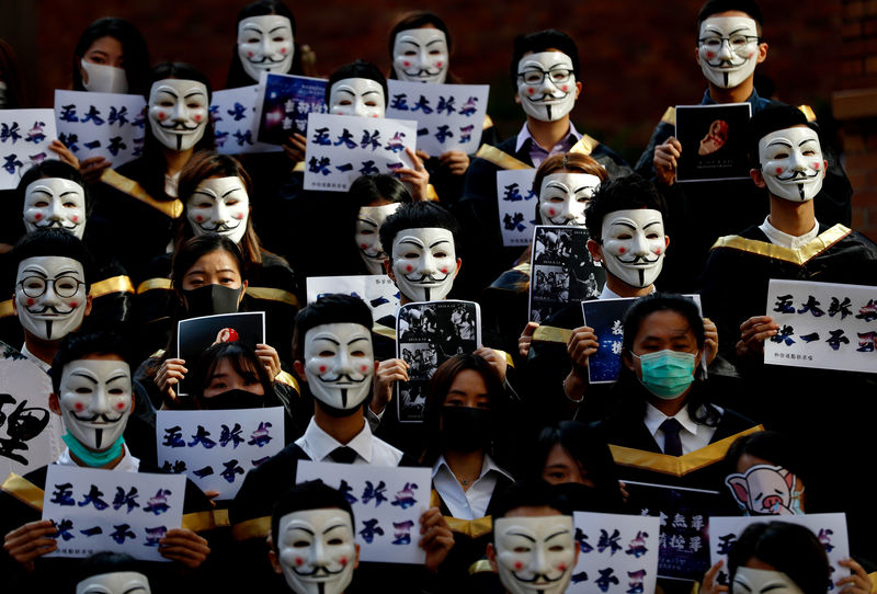 © Reuters. University students wearing Guy Fawkes masks pose for a photoshot to support anti-government protests before their graduation ceremony at the Hong Kong Polytechnic University in Hong Kong