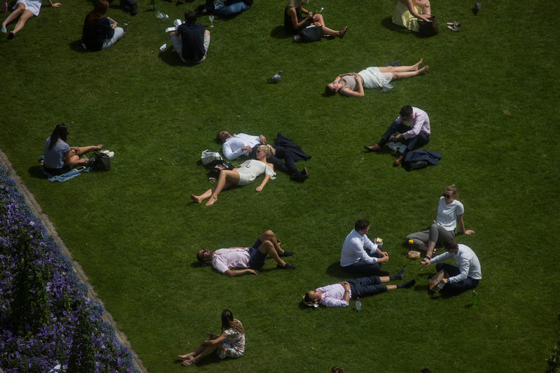 © Reuters. FILE PHOTO: Workers sit on green during a lunch break as they enjoy the hot weather in London