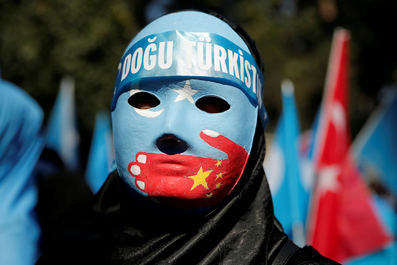 © Reuters. FILE PHOTO: An ethnic Uighur demonstrator wears a mask as she attends a protest against China in front of the Chinese Consulate in Istanbul
