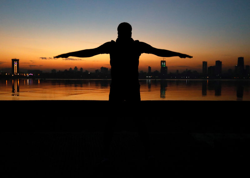 © Reuters. FILE PHOTO: A man exercises early in the morning along the Arabian Sea in Mumbai, India