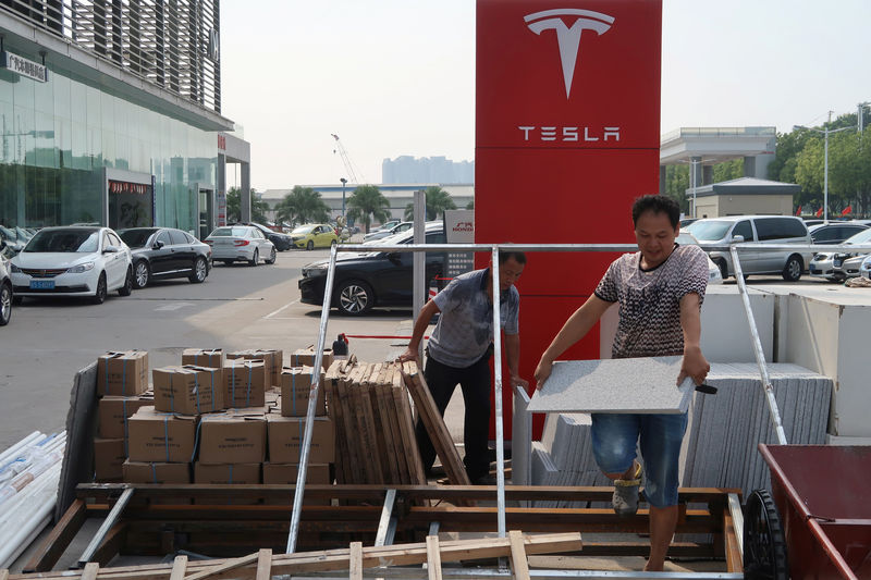 © Reuters. Workers carry building materials for a new Tesla showroom in Guangzhou