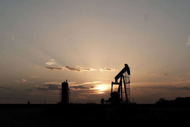 © Reuters. Oil pump jacks work at sunset near Midland