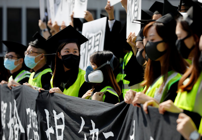 طلاب بأقنعة يهتفون بشعارات المحتجين في حفل تخرجهم في هونج كونج