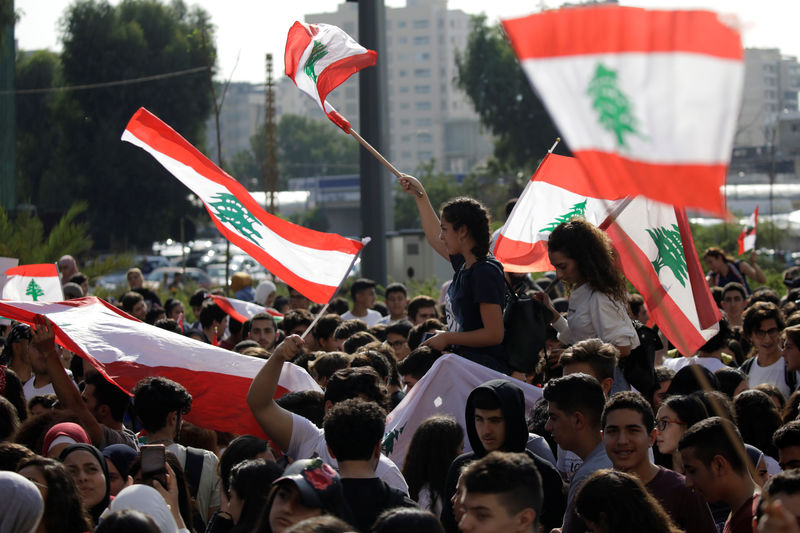 © Reuters. Students carry national flags during ongoing anti-government protests in Beirut