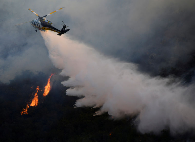 © Reuters. FILE PHOTO: A firefighting helicopter makes a water drop on the Getty Fire as it burns in the hills of West Los Angeles, California
