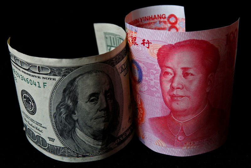 © Reuters. FILE PHOTO: A 100 yuan banknote is placed next to a $100 banknote in this picture illustration taken in Beijing