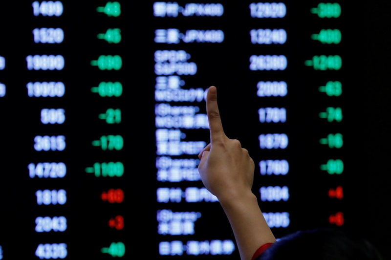 © Reuters. A woman points to an electronic board showing stock prices as she poses in front of the board after the New Year opening ceremony at the Tokyo Stock Exchange (TSE), held to wish for the success of Japan's stock market, in Tokyo