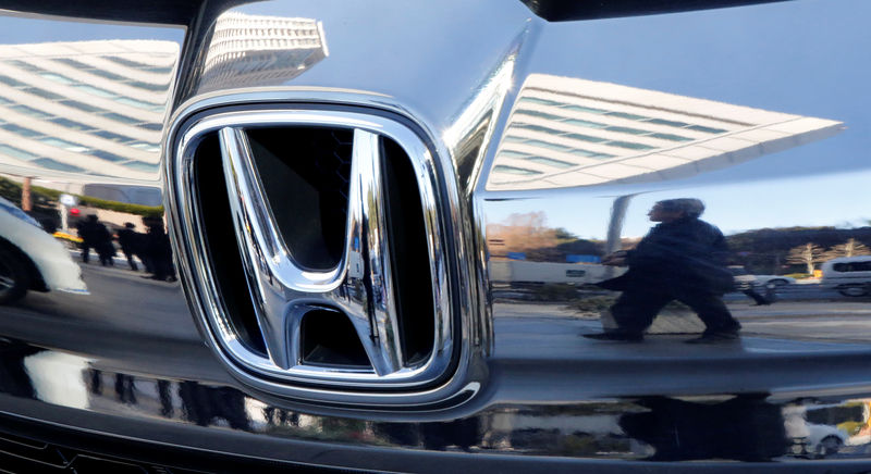 © Reuters. People are reflected on a Honda Motor car outside the company's headquarters in Tokyo