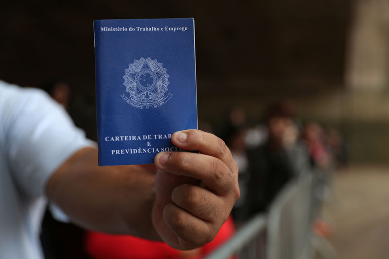 © Reuters. Homem segura carteira de trabalho em fila à procura de emprego