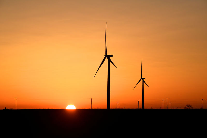 © Reuters. FILE PHOTO: Wind turbines operate at sunrise in the Permian Basin oil and natural gas production area in Big Spring