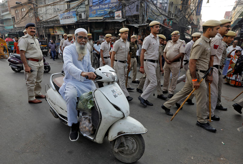 © Reuters. A Muslim man rides a scooter as police officers conduct a flag march in a street outside Jama Masjid, before Supreme Court's verdict on a disputed religious site claimed by both majority Hindus and Muslim in Ayodhya, in Delhi