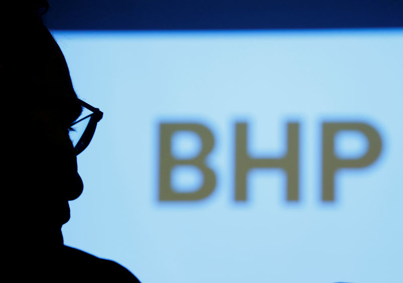 © Reuters. FILE PHOTO: A BHP executive is silhouetted against a screen projecting the company's logo.