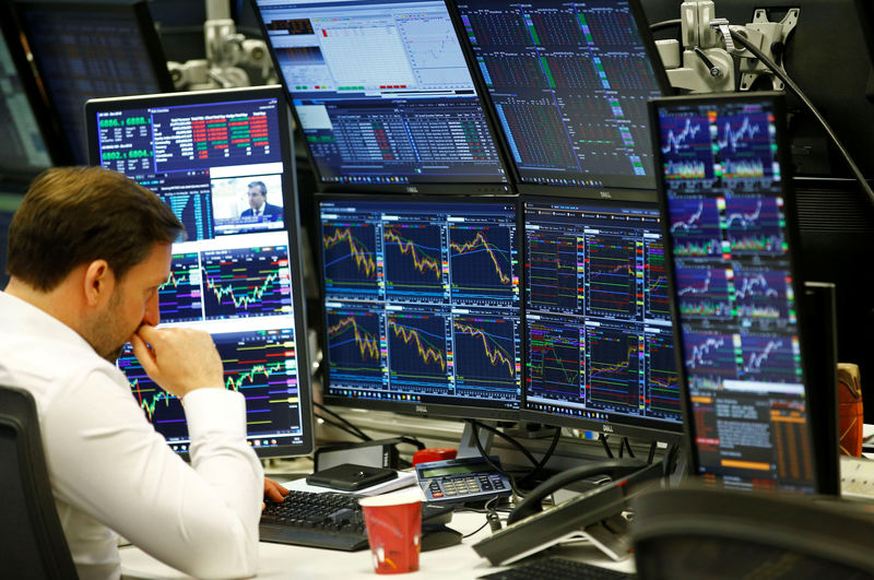 © Reuters. Traders work at their desks whilst screens show market data at CMC Markets in London