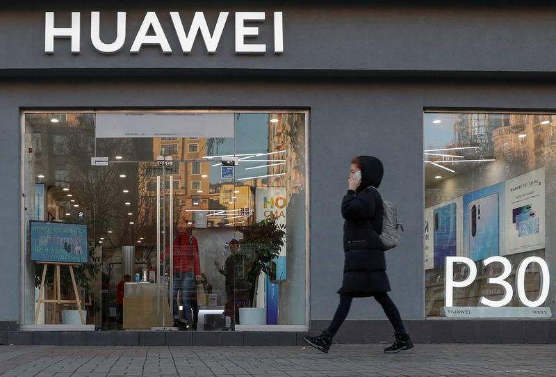 © Reuters. A woman speaks on her mobile phone as she walks past a Huawei store in central Kiev