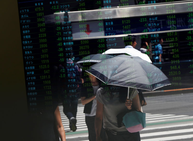 © Reuters. Passersby are reflected on a stock quotation board outside a brokerage in Tokyo