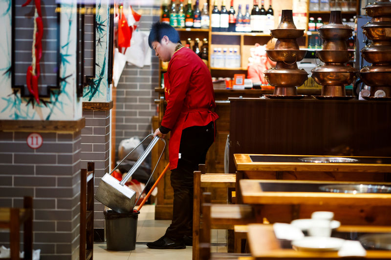 © Reuters. A waiter cleans the floor of a restaurant after closing hours in Beijing