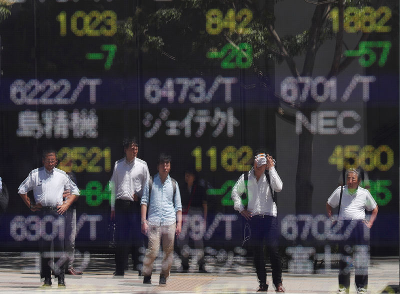 © Reuters. FILE PHOTO: Passersby are reflected on a stock quotation board outside a brokerage in Tokyo