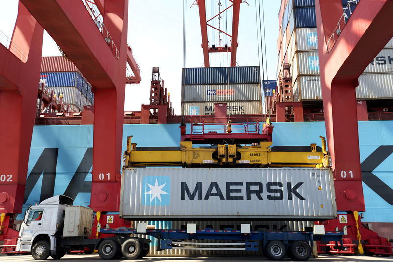 © Reuters. FILE PHOTO: Truck transports a Maersk shipping container by a cargo ship at a port in Qingdao