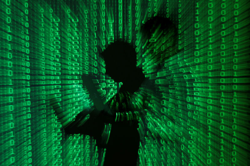 © Reuters. FILE PHOTO: An illustration picture shows projection of binary code on man holding aptop computer in Warsaw