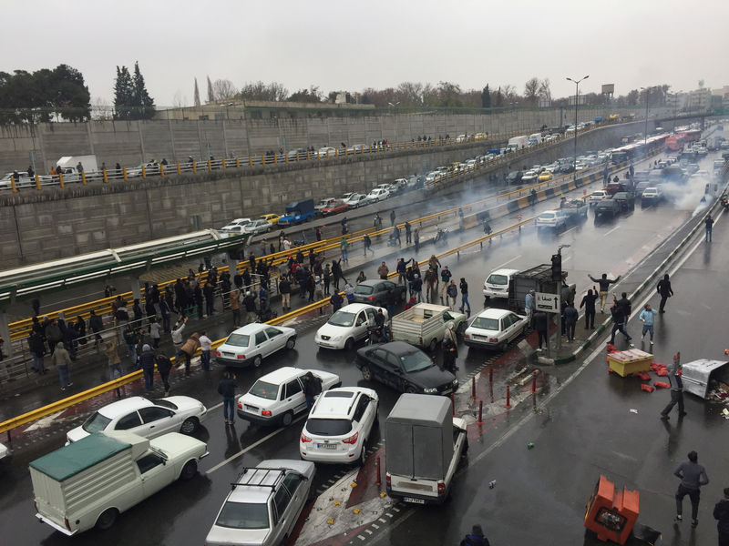 © Reuters. People stop their cars in a highway to show their protest for increased gas price in Tehran