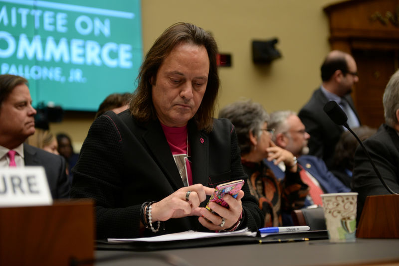 © Reuters. T-Mobile US CEO Legere checks his phone before testifying before a U.S. House Committee on Energy and Commerce Subcommittee hearing in Washington