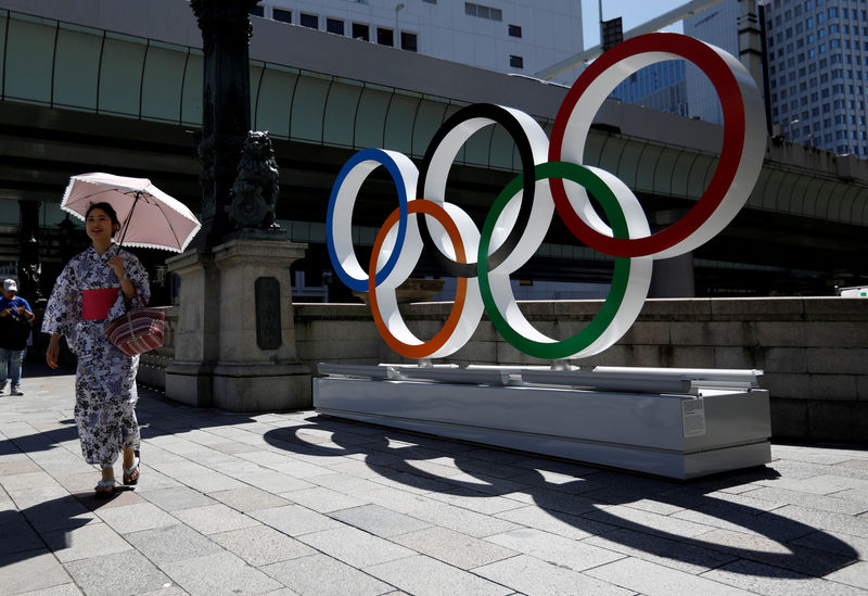 © Reuters. FILE PHOTO: A woman wearing the yukata, or casual summer kimono, walks past Olympic rings displayed at Nihonbashi district in Tokyo