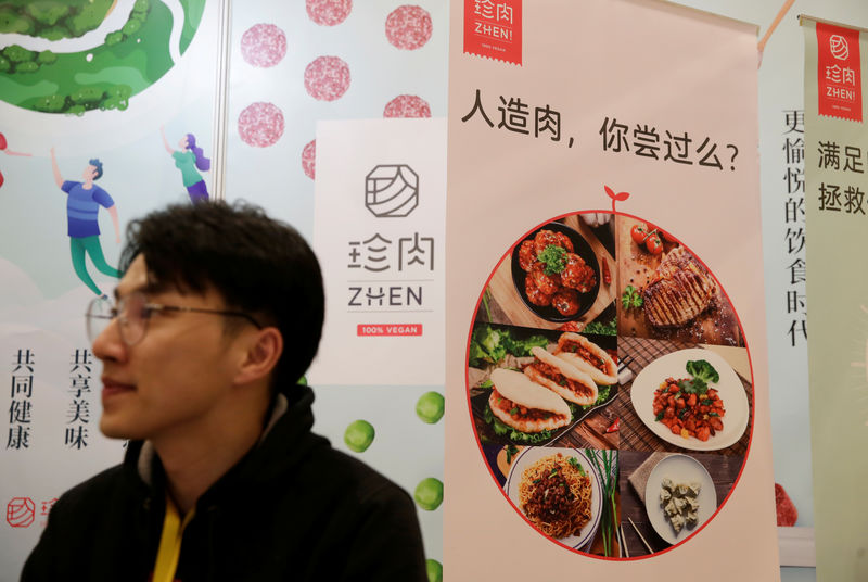 © Reuters. A man sits next to a poster at the booth of plant-based food company Zhenmeat at VeggieWorld fair in Beijing