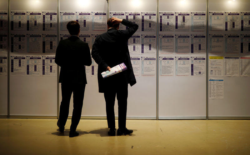 © Reuters. FILE PHOTO: Men look at recruiting information during a job fair in Seoul