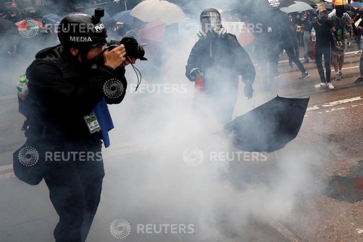 © Reuters. A media photographer takes a photo in a cloud of tear gas during an anti-government rally in central Hong Kong