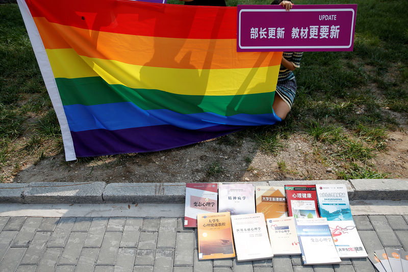 © Reuters. Partidarios sostienen una bandera arco iris y una pancarta cerca del tribunal antes de la audiencia en la que un estudiante chino presentó una demanda contra el Ministerio de Educación por los libros de texto escolares que describen la homosexualidad como un trastorno mental, en Pekín, China, el 12 de septiembre de 2016