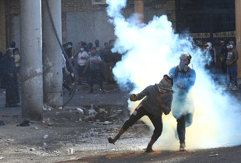 © Reuters. An Iraqi demonstrator throws away a tear gas canister during the ongoing anti-government protests in Baghdad