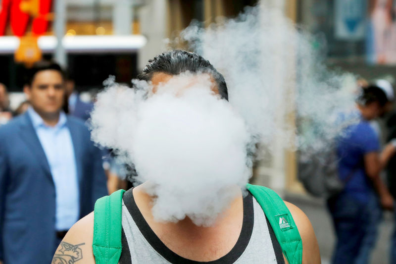 © Reuters. FILE PHOTO: A man uses a vape as he walks on Broadway in New York City