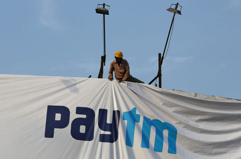 © Reuters. FILE PHOTO: A worker adjusts a hoarding of Paytm, a digital payments firm, in Ahmedabad